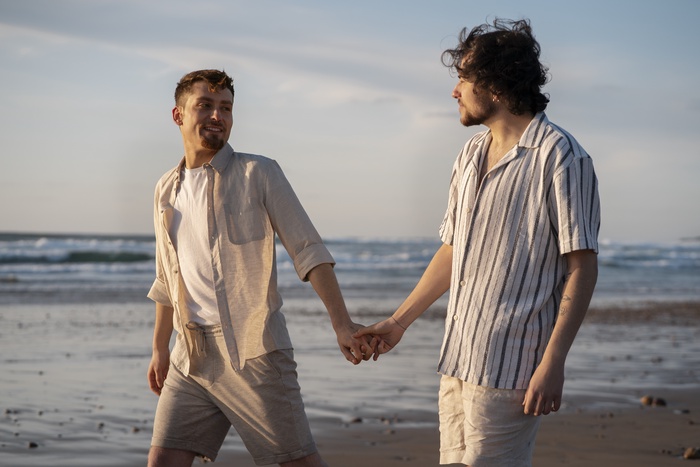 Smiling gay couple relaxing together on the beach.